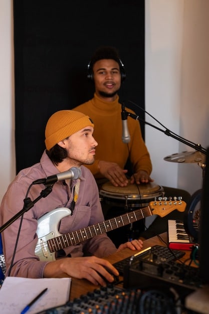 A diverse group of musicians collaborating in a recording studio, with laptops, instruments, and microphones visible. The atmosphere is creative and collaborative, showcasing the process of music-making.