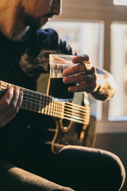 A close-up shot of a musician's hands playing an acoustic guitar on stage during a live performance. The background is blurred, focusing on the intricate finger movements and the warm lighting on the instrument.