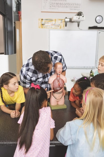 A celebrity teaching a group of children in a classroom. The children are attentive and engaged, with books and other learning materials visible. The scene shows a positive and supportive educational environment.