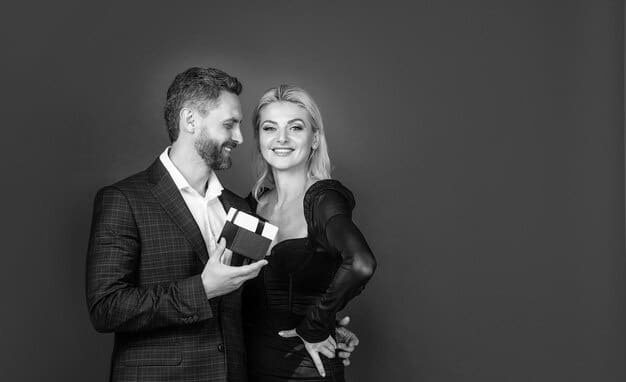 A black and white candid photo of a celebrity couple laughing together during an awards show after-party. They are dressed in glamorous attire and appear affectionate.
