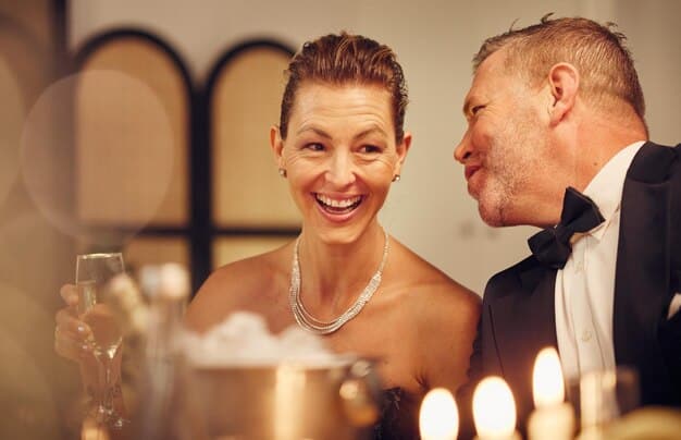 A candid shot of a celebrity couple during their wedding reception. The couple is laughing and sharing a private joke, surrounded by close friends and family. Soft, warm lighting creates an intimate and joyful atmosphere.