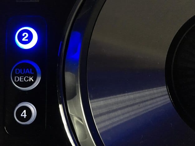 A close-up of a high-end 4K Blu-ray player's control panel, showing a disc tray open and glowing display, surrounded by quality components.