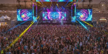 2026 Music Festival Trends: Immersive Experiences & Tech Integration Thousands of people enjoying a vibrant music festival at sunset with colorful lights and digital art.