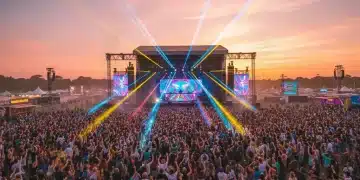 Vibrant crowd enjoying a music festival at sunset with bright stage lights