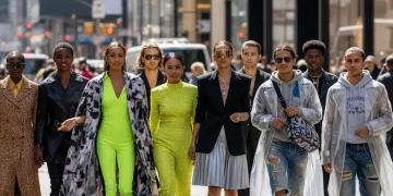 Diverse individuals in avant-garde street fashion on a city street, luxury stores in background.