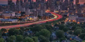 Panoramic view of a modern city skyline and a green suburban neighborhood at dusk, illustrating urban-suburban population shifts.